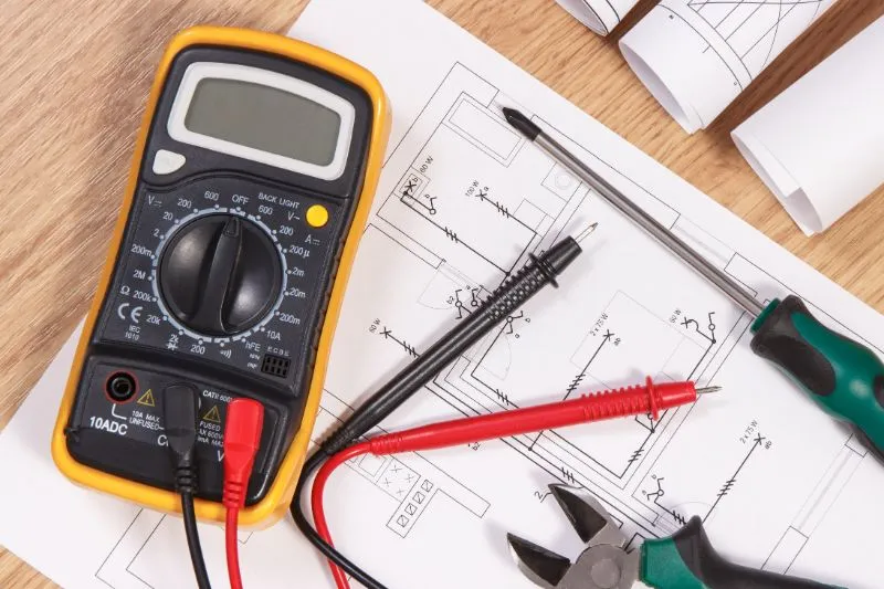 Multimeter and wiring diagrams used to test an electrical panel